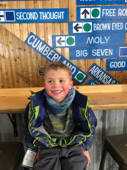 Kid in lodge by old signs — Denise Schnider